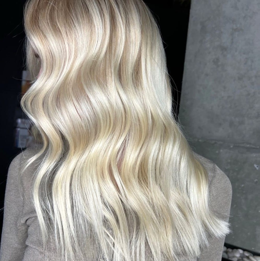 Back view of wavy platinum blonde hair in a salon