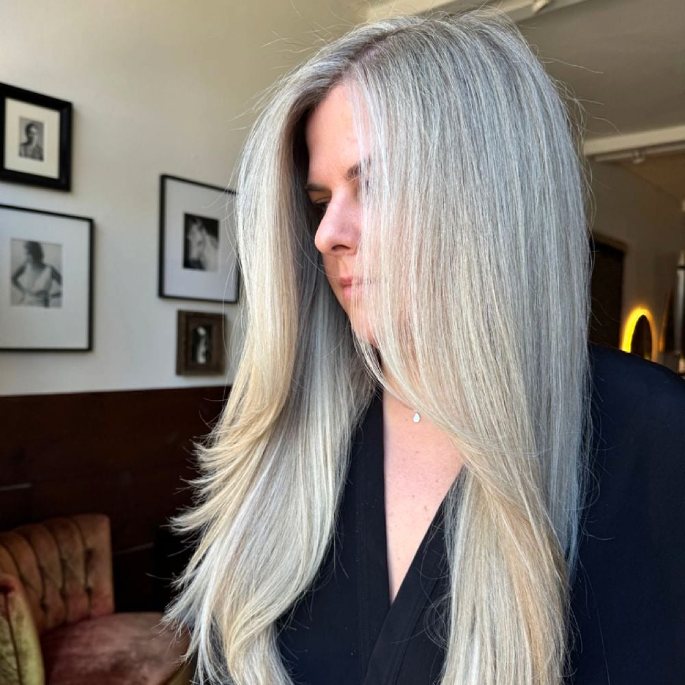 Long silver-blonde hair in profile inside a decorated salon